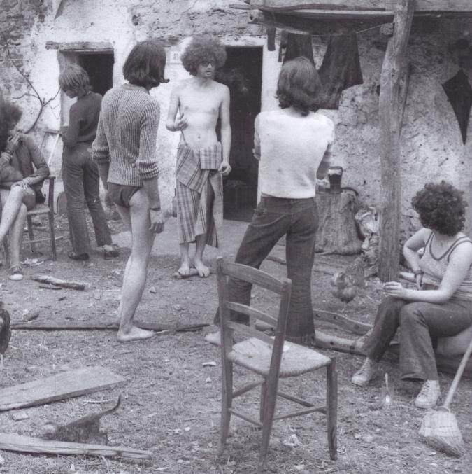 Die Ovada Kommune. Menschen stehen vor einem Bauernhaus