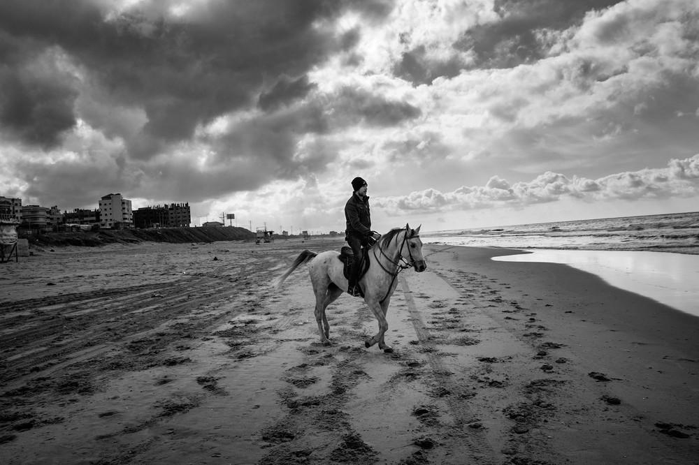 A man rides his horse on the beach in Gaza