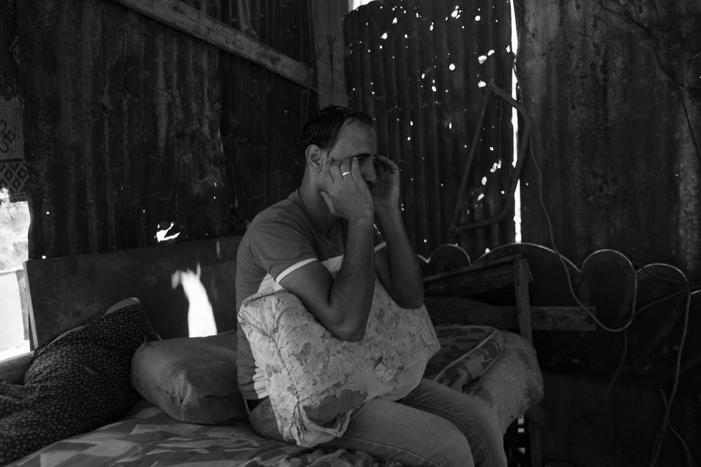 A man in the garden of his destroyed home, suffering from headaches due to high stress